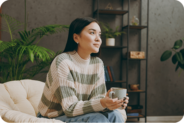 Dreamy, smiling woman sitting on a couch, representing curiosity